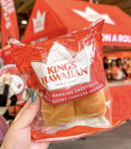 A hand holding a package of King's Hawaiian Sweet Rolls.